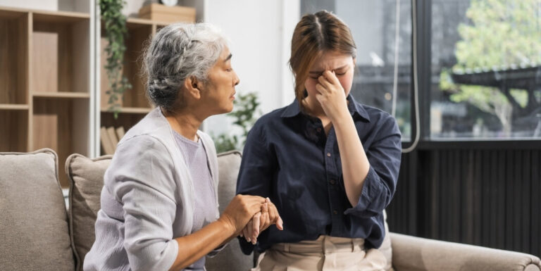Elderly Woman Comforting a Distressed Young Woman Indoors at a Memory Care Facility